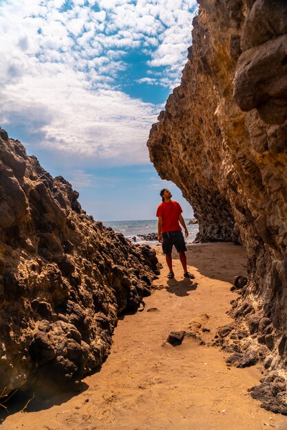 Ein junger Mann, der die schönen Felsen an der Küste bei Cala de la Media Luna im Naturpark Cabo de Gata, Nijar, Andalusien genießt. Spanien, Mittelmeer