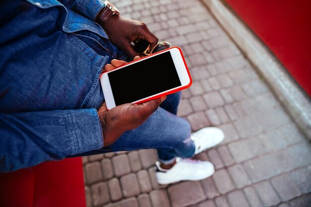 Ein junger Mann, der ein Handy auf der Straße hält