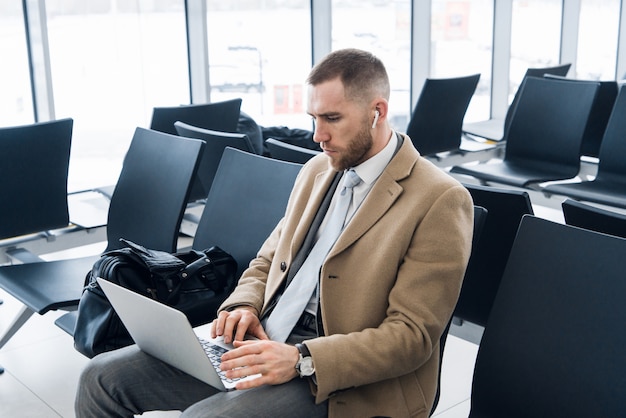 Ein junger Mann, der einen Laptop in einem Flughafenterminal benutzt