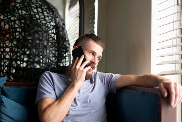 Ein junger Mann, der im Café sitzt und mit dem Handy spricht