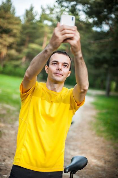 Ein junger Mann, der mit seinem Fahrrad ein Selfie macht