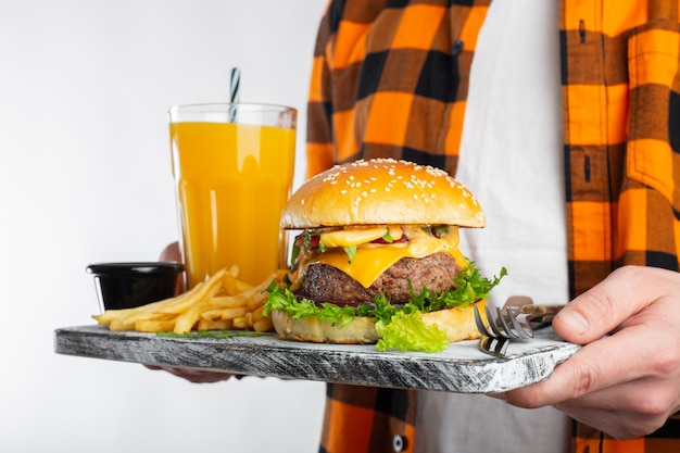 Ein junger Mann hält einen frischen Burger.