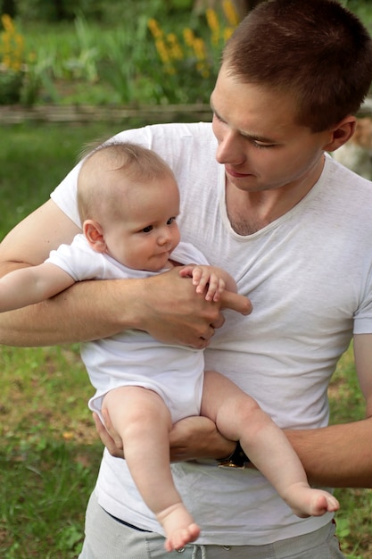 Ein junger Mann hält und sieht das Baby an.