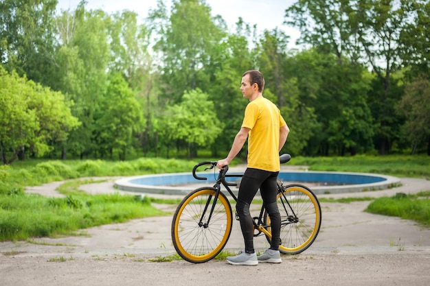 Ein junger Mann hielt an, um sich mit seinem Fahrrad in einem öffentlichen Park auszuruhen. Er genießt einen frühen sonnigen Morgen im Wald