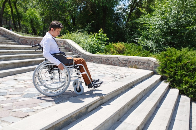 Ein junger Mann im Rollstuhl, der die Treppe nicht hinuntersteigen kann.