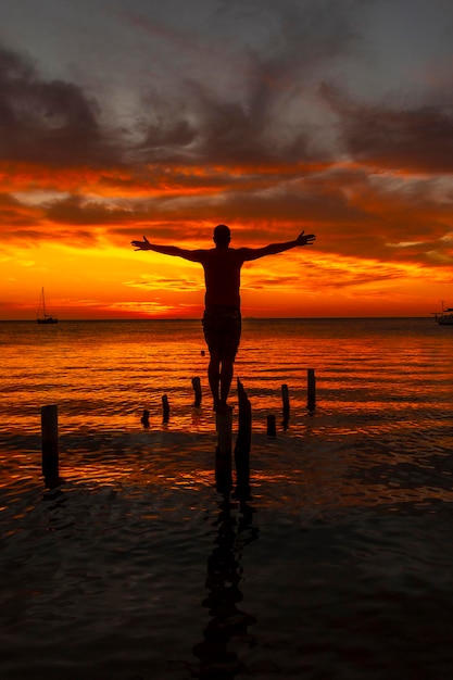 Ein junger Mann im Wasser am Orange Sunset am West End Strand von Roatan