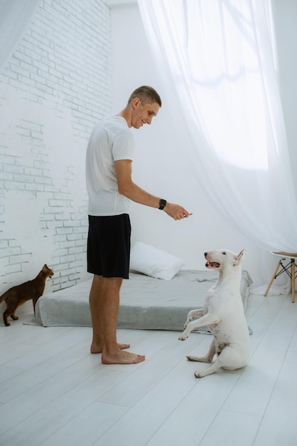 ein junger Mann in einem hellen Raum spielt mit einem Hund