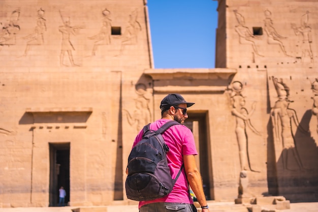 Ein junger Mann in einem rosa Hemd im Tempel von Philae, eine griechisch-römische Konstruktion, ein Tempel, der Isis, der Göttin der Liebe, gewidmet ist. Assuan. ägyptisch