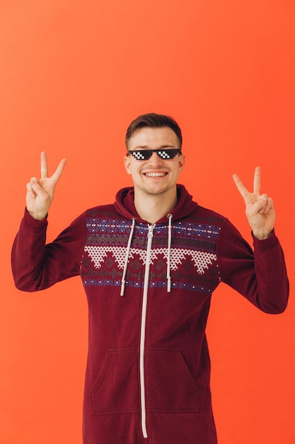 Ein junger Mann in einem weihnachtlichen Kigurumi und Sonnenbrille auf farbigem Hintergrund