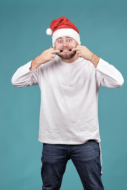 Ein junger Mann in einer Weihnachtsmütze, der ein Gesicht verzieht, streckt seinen Mund aus