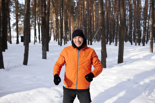 Ein junger Mann in heller Sportkleidung rennt an einem Wintertag gerne durch den Wald