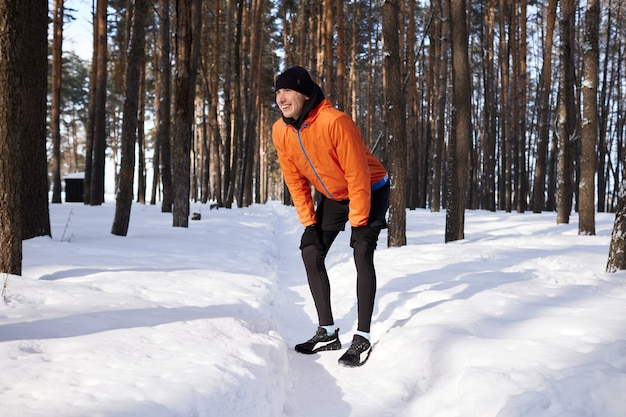 Ein junger Mann in heller Sportkleidung rennt an einem Wintertag gerne durch den Wald