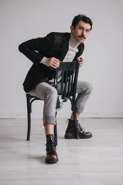 Foto ein junger mann in jeans und jacke posiert im studio vor einer weißen wand