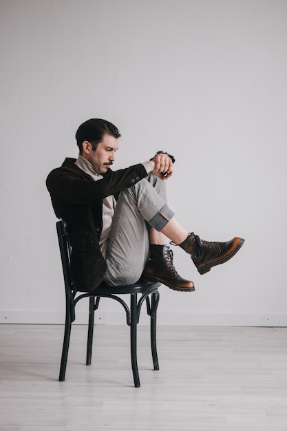 Foto ein junger mann in jeans und jacke posiert im studio vor einer weißen wand