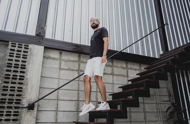 Ein junger Mann in T-Shirt und Shorts auf der Treppe in den Straßen der Stadt