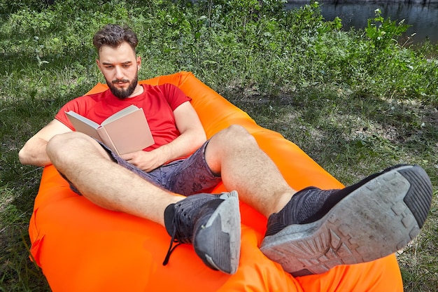 Foto ein junger mann in voller länge benutzt sein handy, während er im freien sitzt