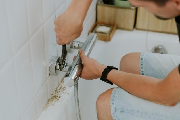 Foto ein junger mann installiert einen wasserhahn im badezimmer