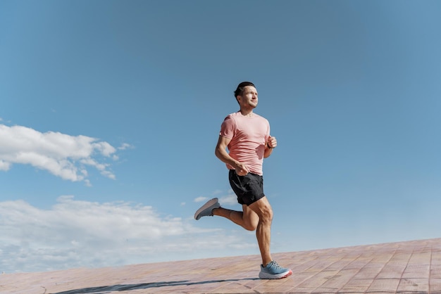 Ein junger Mann joggt in T-Shirt und Shorts allein auf einem Laufband in der Stadt. Aktiver Lebensstil