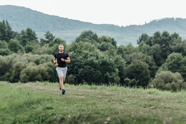 Ein junger Mann joggt in voller Länge auf einem grasbewachsenen Feld