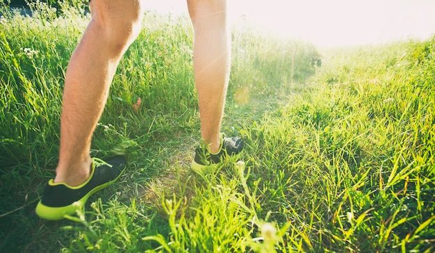 Ein junger mann joggt querfeldein durch den weg auf der wiese