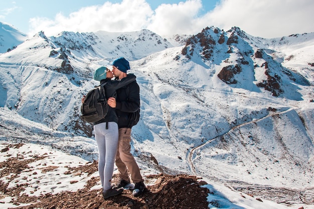 Ein junger Mann küsst seine Frau vor dem Hintergrund der schneebedeckten Berge Urlaub in den Bergen