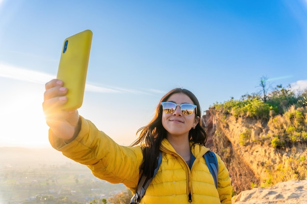 Ein junger Mann macht ein Selfie mit einem Smartphone auf dem Gipfel des Berges, ein Konzept für Freiheit in der Natur