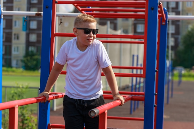 Ein junger Mann macht im Sommer Liegestütze auf Bars auf einem Sportplatz. Foto in hoher Qualität