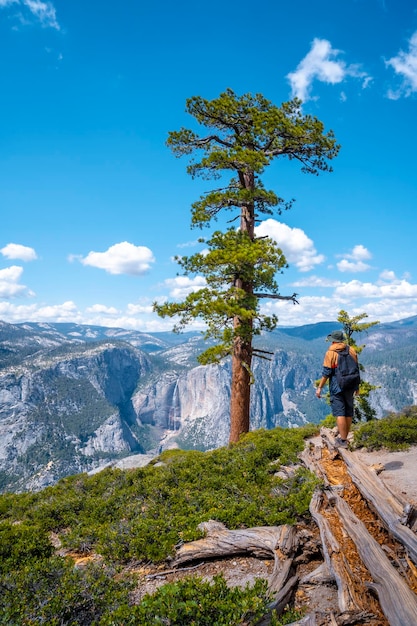 Ein junger Mann mit brauner Jacke im Sentinel Dome mit Blick auf Upper Yosemite Fall