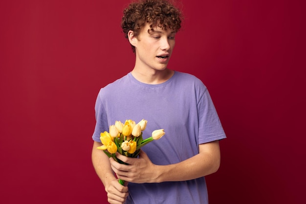 Ein junger Mann mit einem gelben Blumenstrauß lila T-Shirts roten Hintergrund unverändert