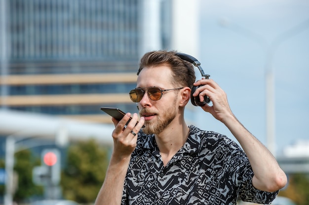 Ein junger Mann mit Kopfhörern und Sonnenbrille hört Musik