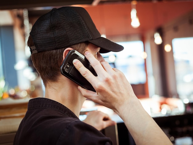 Ein junger Mann mit Mütze telefoniert mit einem Handy