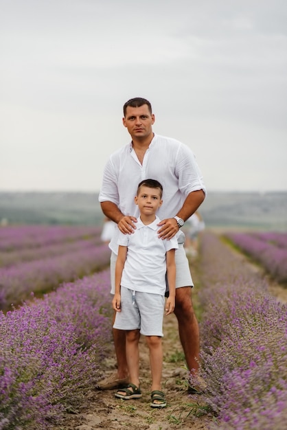 Ein junger Mann mit seinem kleinen Sohn geht durch ein wunderschönes Lavendelfeld und genießt den Duft von Blumen. Ruhe und schöne Natur. Einheit mit der Natur und Harmonie.