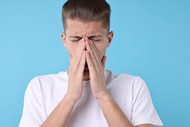 Ein junger Mann mit Sinusitis auf hellblauem Hintergrund