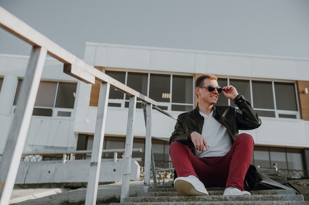 ein junger mann mit sonnenbrille sitzt auf den treppen in der straßenstadt