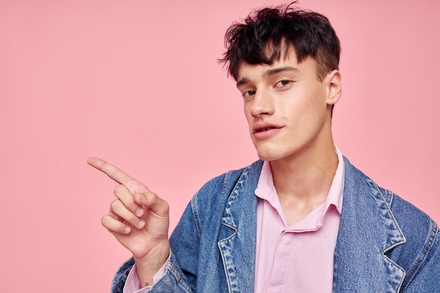 Ein junger Mann Mode Frisur posiert Kleidung Jeansjacke modernen Stil rosa Hintergrund unverändert