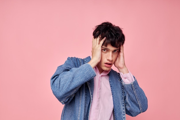 Ein junger Mann Mode Frisur posiert Kleidung Jeansjacke modernen Stil rosa Hintergrund unverändert