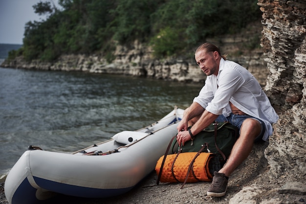 Ein junger Mann reist mit einem Rucksack mit einem Boot. Die Lebensweise des Reisens und der Natur mit der Natur