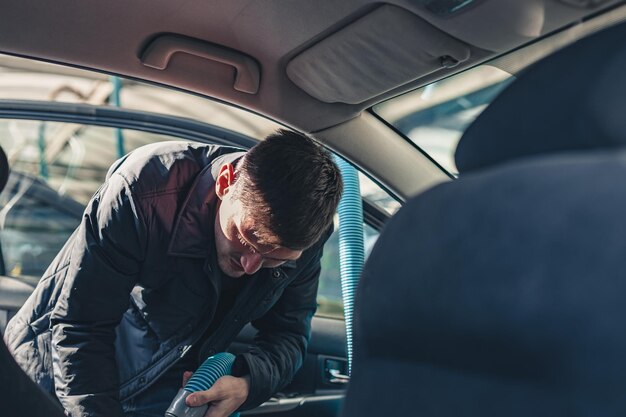 Ein junger Mann saugt den Innenraum eines Autos