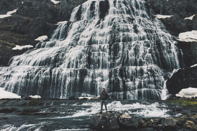 Foto ein junger mann schaut ab, während er im winter gegen einen wasserfall steht