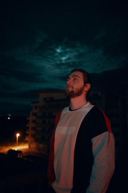 Ein junger Mann schaut sich die beleuchtete Stadt gegen den Nachthimmel an