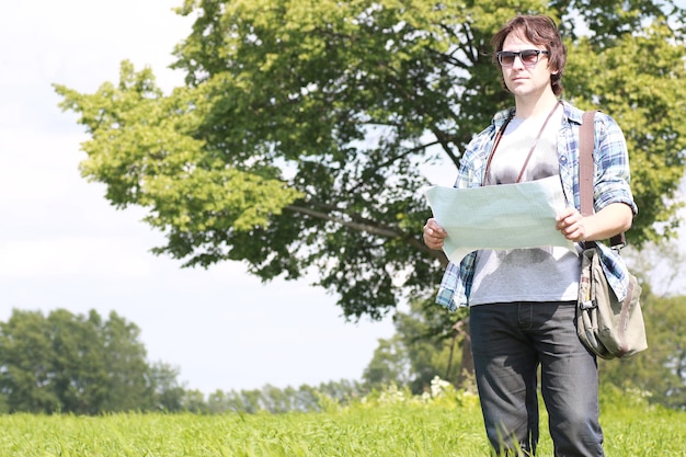 Ein junger Mann schaut sich eine Landkarte in der Natur an, um sich nicht zu verirren