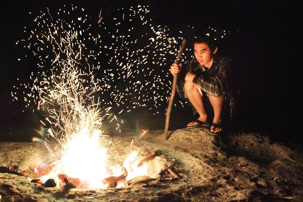 Foto ein junger mann sitzt am lagerfeuer