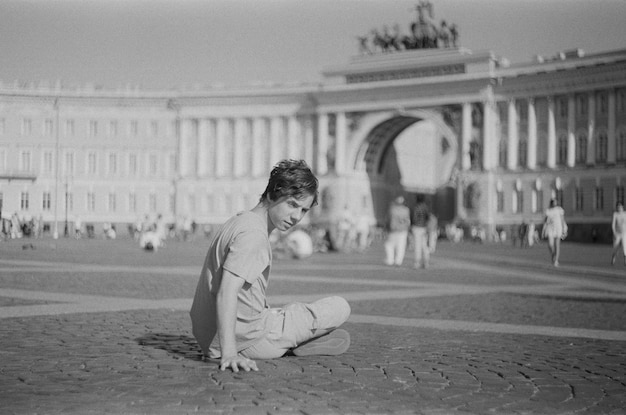 Ein junger Mann sitzt auf dem Dvortsovaya-Platz in St. Petersburg