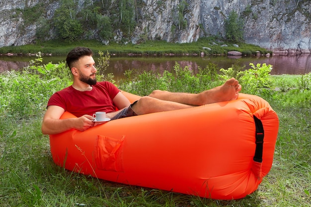 Foto ein junger mann sitzt auf dem gras am see