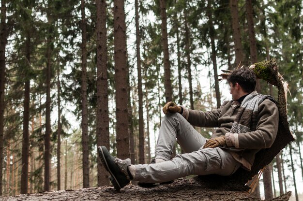 Foto ein junger mann sitzt auf einem baumstamm im wald