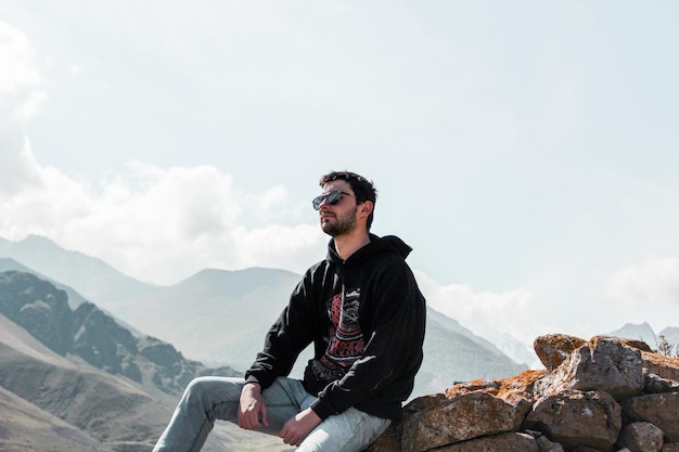 Ein junger Mann sitzt auf Felsen gegen den Himmel