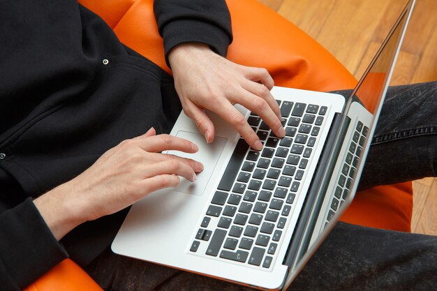 Ein junger Mann sitzt in einem Sessel und arbeitet an einem Computer.