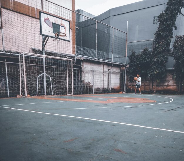 Foto ein junger mann spielt auf einem basketballplatz