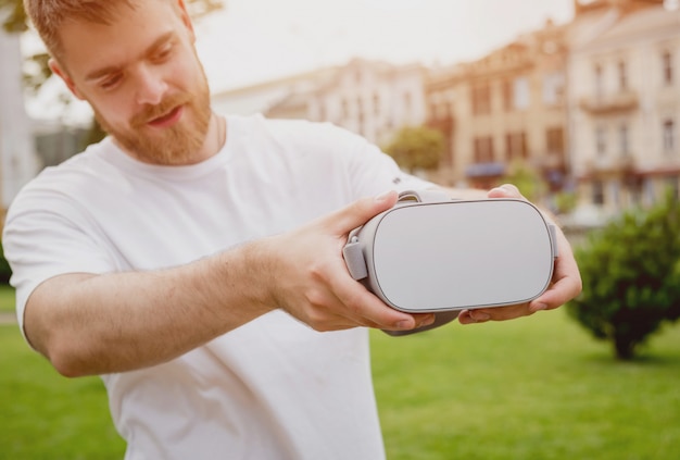 Ein junger Mann spielt ein Spiel mit einer Virtual-Reality-Brille auf der Straße.