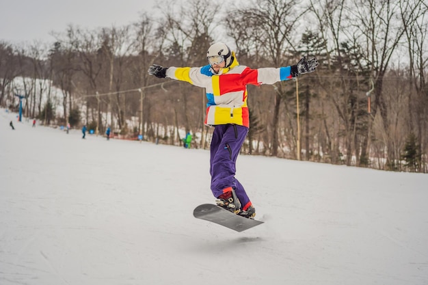 Foto ein junger mann springt mit einem snowboard in den bergen